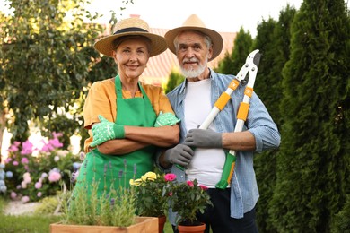 Photo of Happy senior couple in gloves and hats in garden