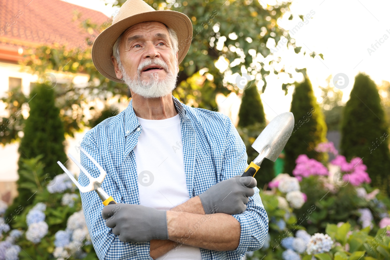 Elderly man in hat with gardening tools outdoors Photo of Elderly man in hat with gardening tools outdoors