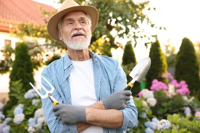 Photo of Elderly man in hat with gardening tools outdoors
