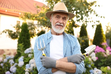 Photo of Portrait of elderly man in hat with gardening tools outdoors