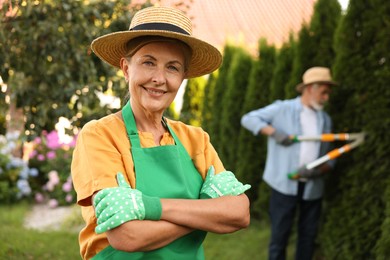 Photo of Senior couple in hats working with plants in garden, selective focus