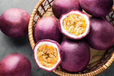 Photo of Fresh passion fruits in wicker basket on grey table, top view