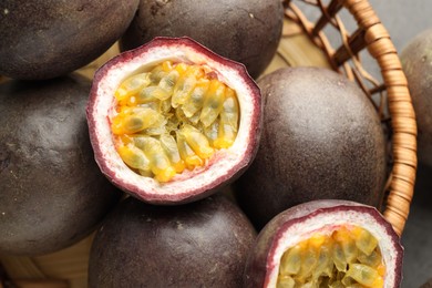 Photo of Fresh passion fruits in wicker basket on table, top view