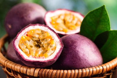 Photo of Fresh passion fruits in wicker basket on table outdoors, closeup