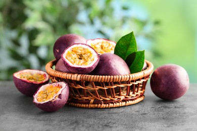 Photo of Fresh passion fruits in wicker basket on grey table outdoors, closeup
