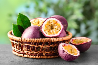 Photo of Fresh passion fruits in wicker basket on grey table outdoors, closeup
