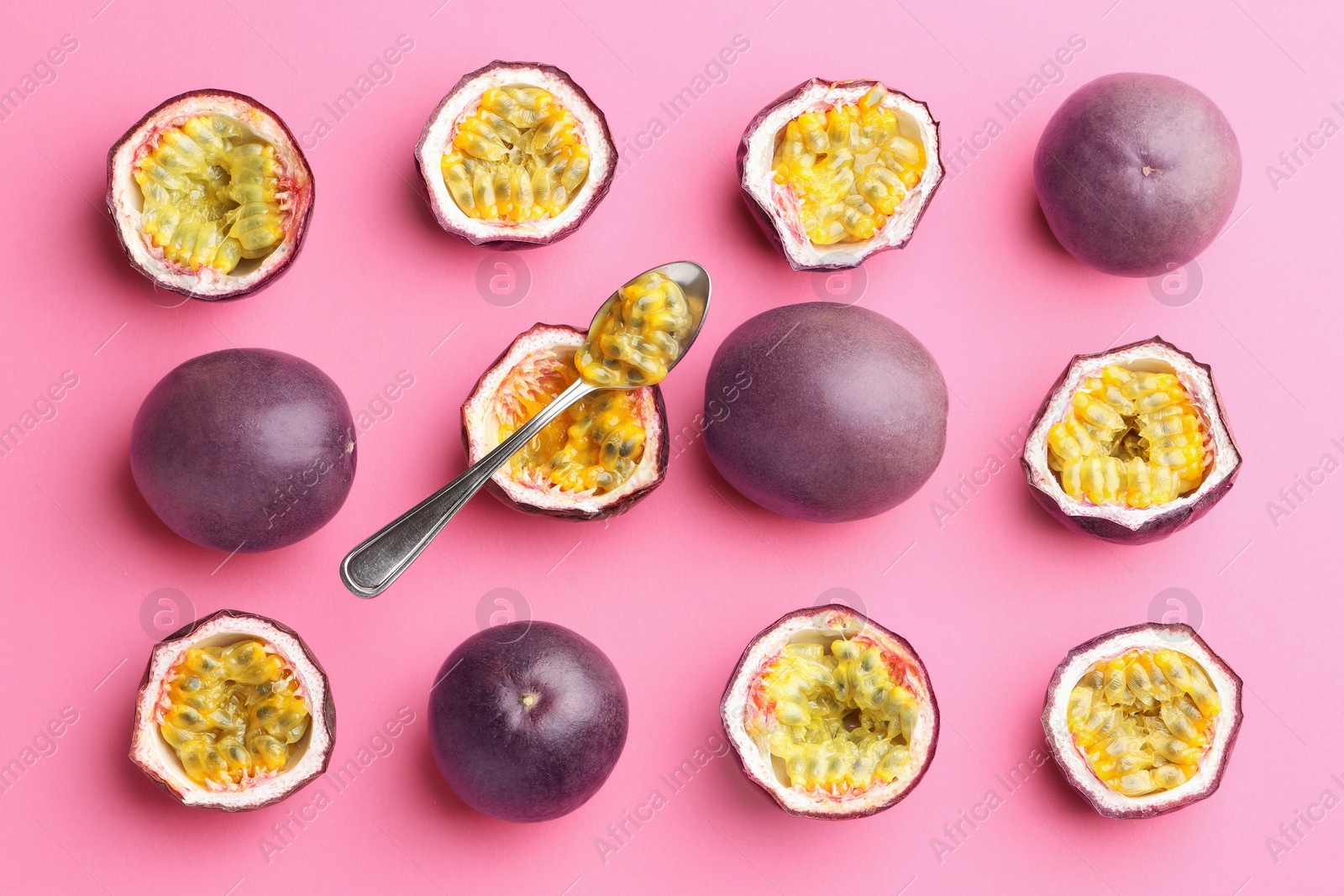 Photo of Fresh passion fruits and spoon on pink background, flat lay
