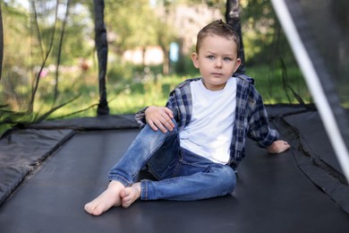 Photo of Cute little boy posing on black trampoline outdoors