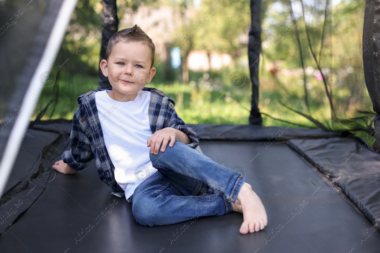 Photo of Cute little boy posing on black trampoline outdoors