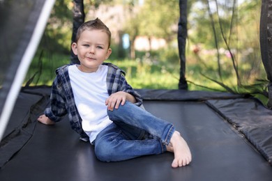 Photo of Cute little boy posing on black trampoline outdoors