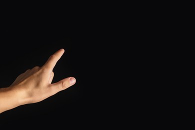Photo of Man touching something on black background, closeup. Space for text