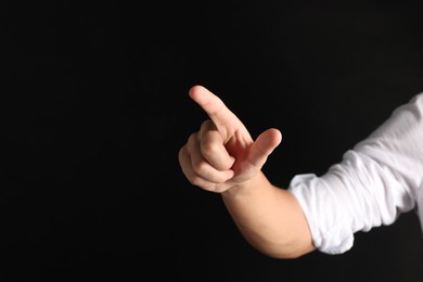 Photo of Man touching something on black background, closeup. Space for text