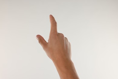 Photo of Man touching something on light grey background, closeup