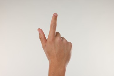 Photo of Man touching something on light grey background, closeup