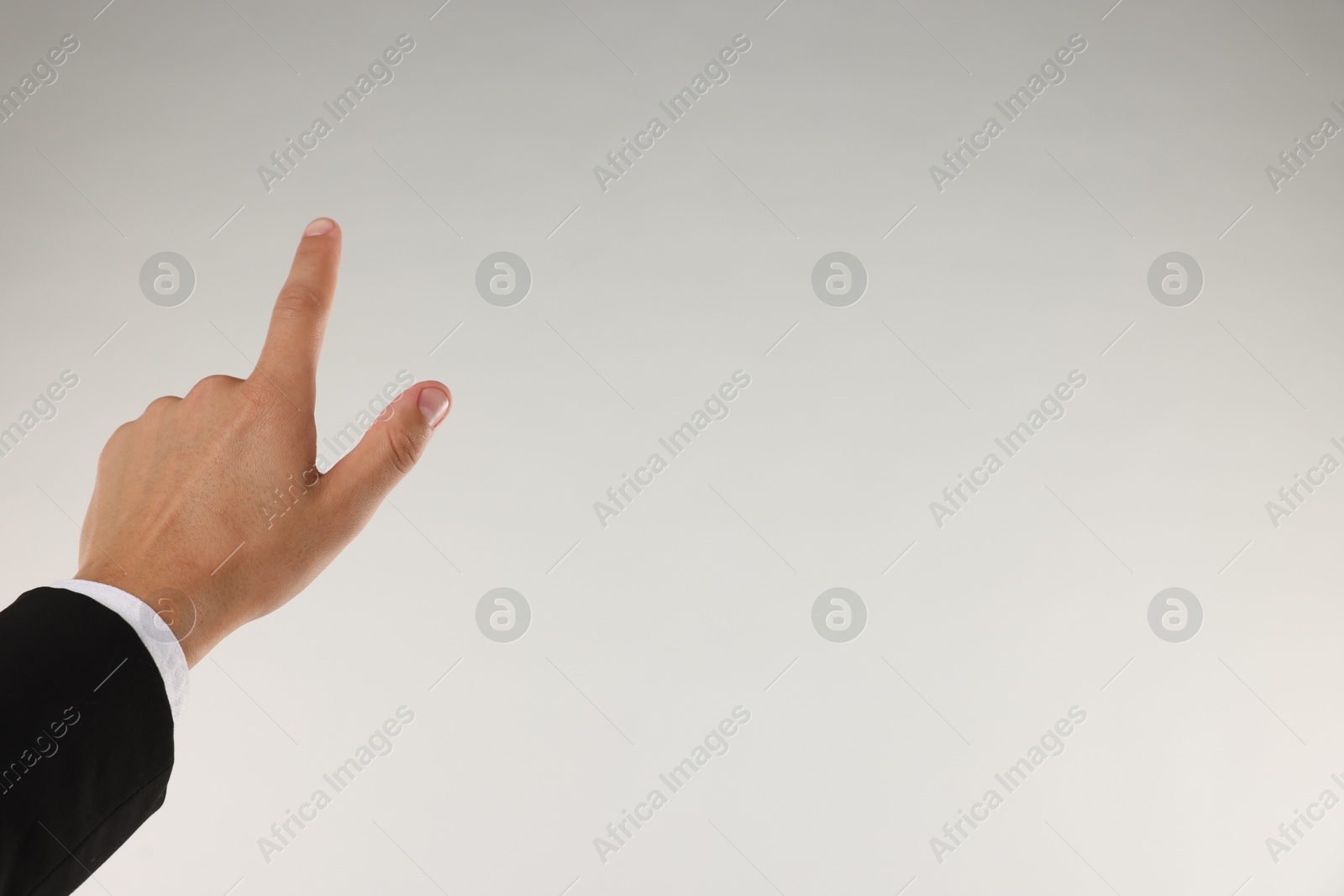Man touching something on light grey background, closeup. Space for text Photo of Man touching something on light grey background, closeup. Space for text