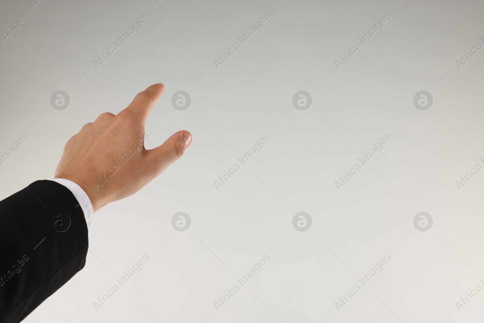 Man touching something on light grey background, closeup. Space for text Photo of Man touching something on light grey background, closeup. Space for text