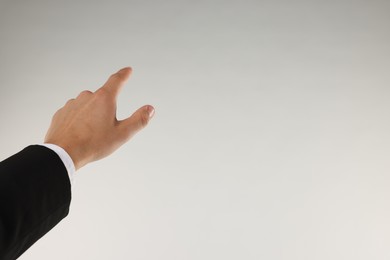 Photo of Man touching something on light grey background, closeup. Space for text