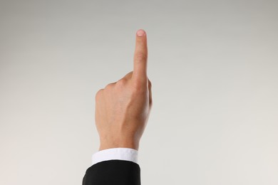 Photo of Man touching something on light grey background, closeup