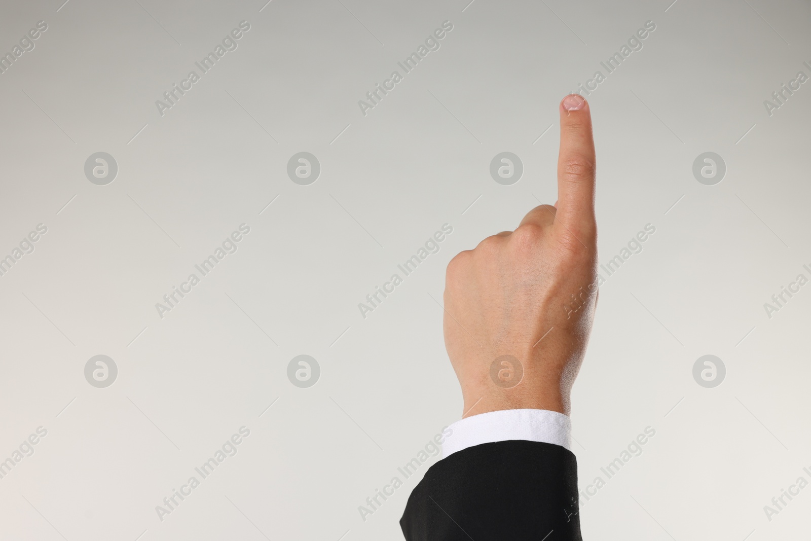 Man touching something on light grey background, closeup. Space for text Photo of Man touching something on light grey background, closeup. Space for text