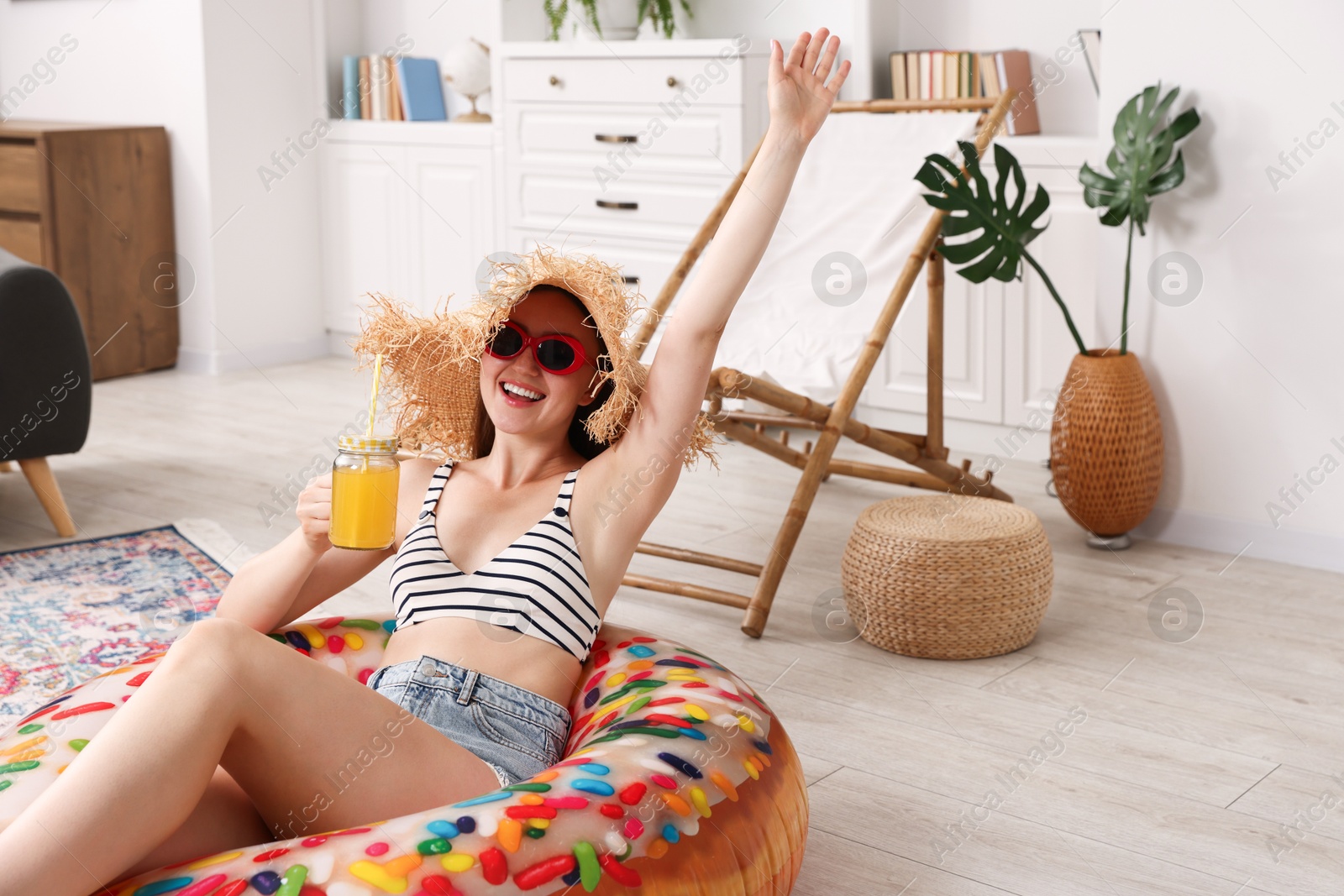 Happy woman in sunglasses and straw hat with mason jar of juice and inflatable ring having fun on floor at home. Dreaming about vacation at sea Photo of Happy woman in sunglasses and straw hat with mason jar of juice and inflatable ring having fun on floor at home. Dreaming about vacation at sea