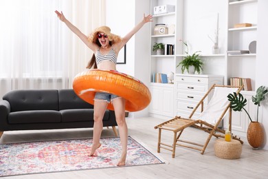 Photo of Happy woman in sunglasses and straw hat with inflatable ring having fun at home. Dreaming about vacation at sea