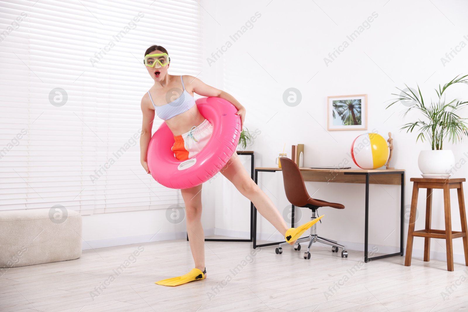 Woman in diving mask and flippers with inflatable ring having fun at home. Dreaming about vacation at sea Photo of Woman in diving mask and flippers with inflatable ring having fun at home. Dreaming about vacation at sea
