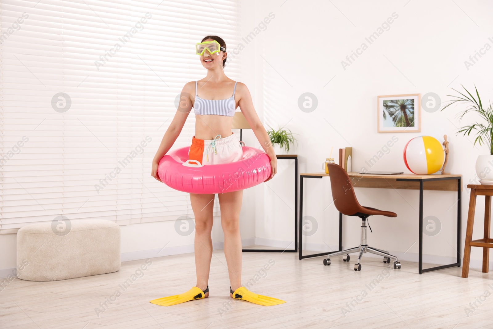 Photo of Happy woman in diving mask and flippers with inflatable ring having fun at home. Dreaming about vacation at sea