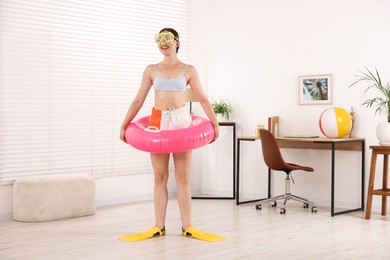 Photo of Happy woman in diving mask and flippers with inflatable ring having fun at home. Dreaming about vacation at sea