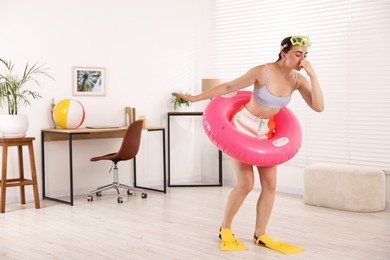 Photo of Woman in diving mask and flippers with inflatable ring having fun at home. Dreaming about vacation at sea
