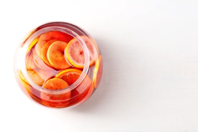 Photo of Tasty fruity punch on white table, top view with space for text. Refreshing drink