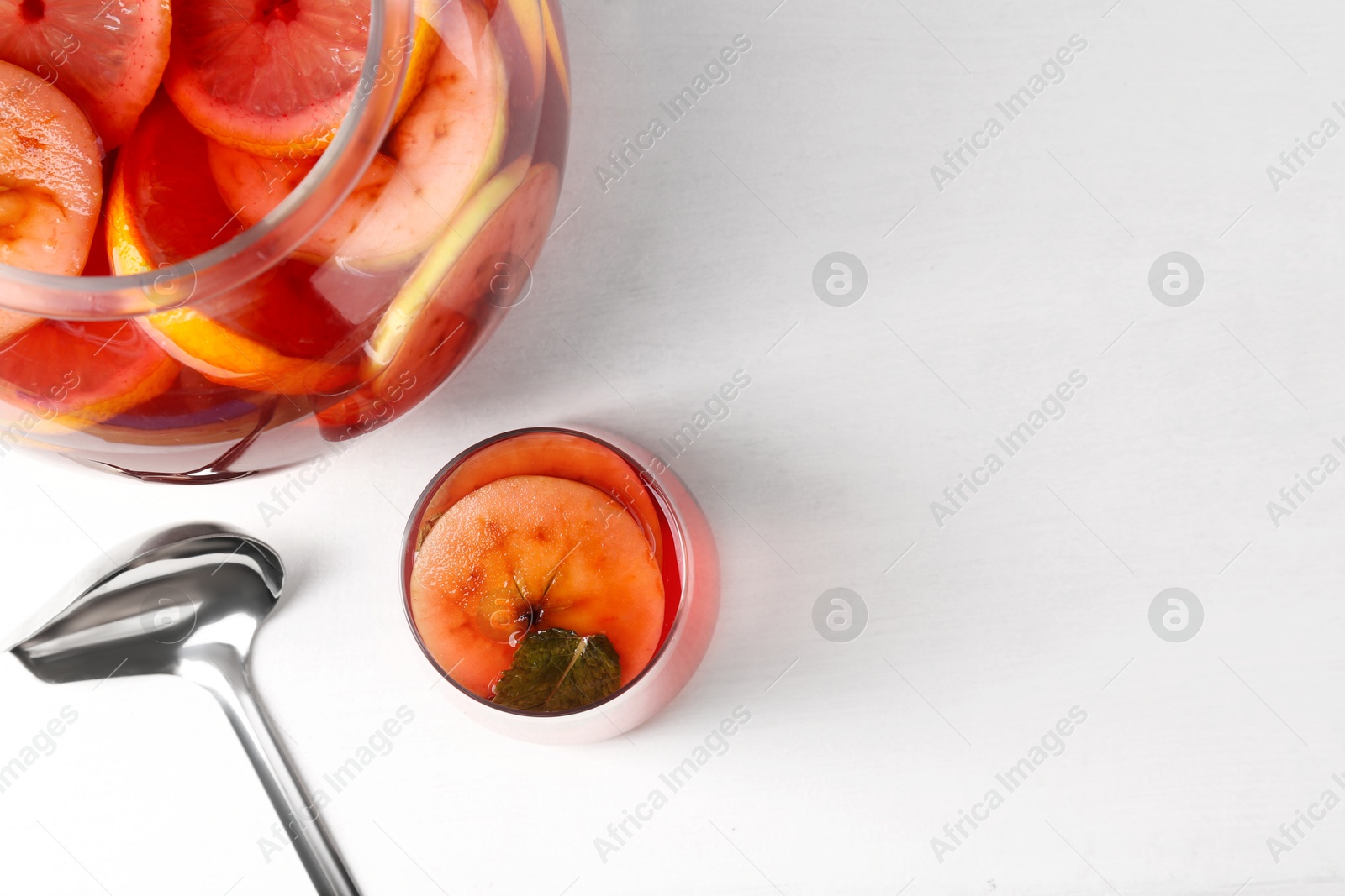 Photo of Tasty fruity punch on white table, top view with space for text. Refreshing drink