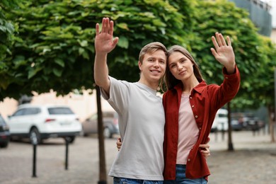 Photo of Goodbye. Lovely couple waving on city street, space for text