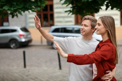 Photo of Goodbye. Lovely couple waving on city street, space for text