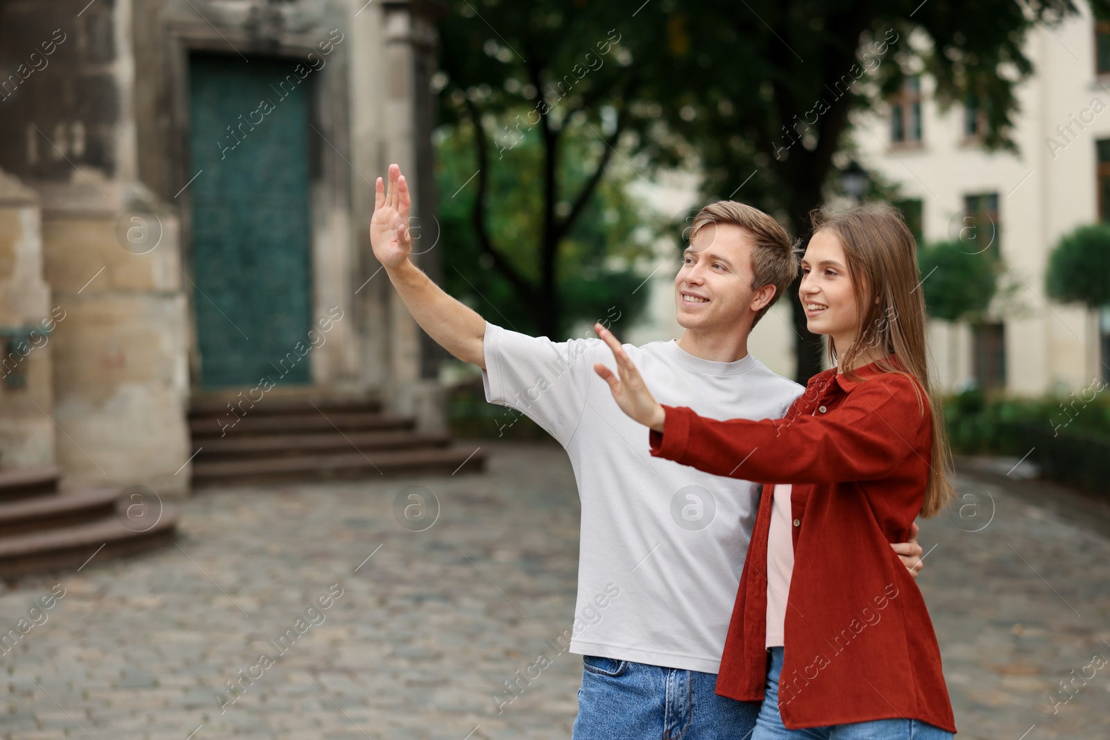 Photo of Goodbye. Lovely couple waving on city street, space for text
