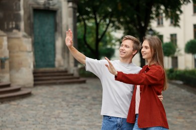 Photo of Goodbye. Lovely couple waving on city street, space for text