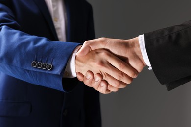Photo of Business partners shaking hands on grey background, closeup
