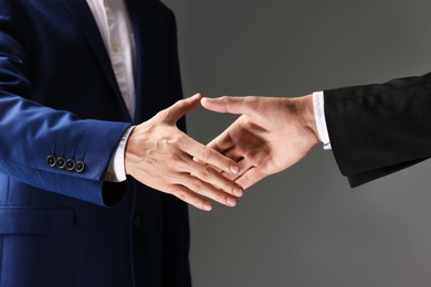 Photo of Business partners shaking hands on grey background, closeup
