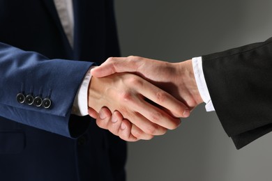 Photo of Business partners shaking hands on grey background, closeup