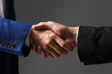 Photo of Business partners shaking hands on grey background, closeup