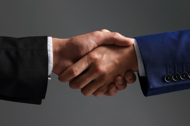 Photo of Business partners shaking hands on grey background, closeup
