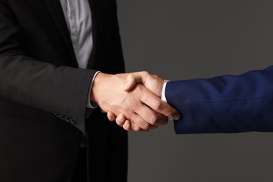 Photo of Business partners shaking hands on grey background, closeup