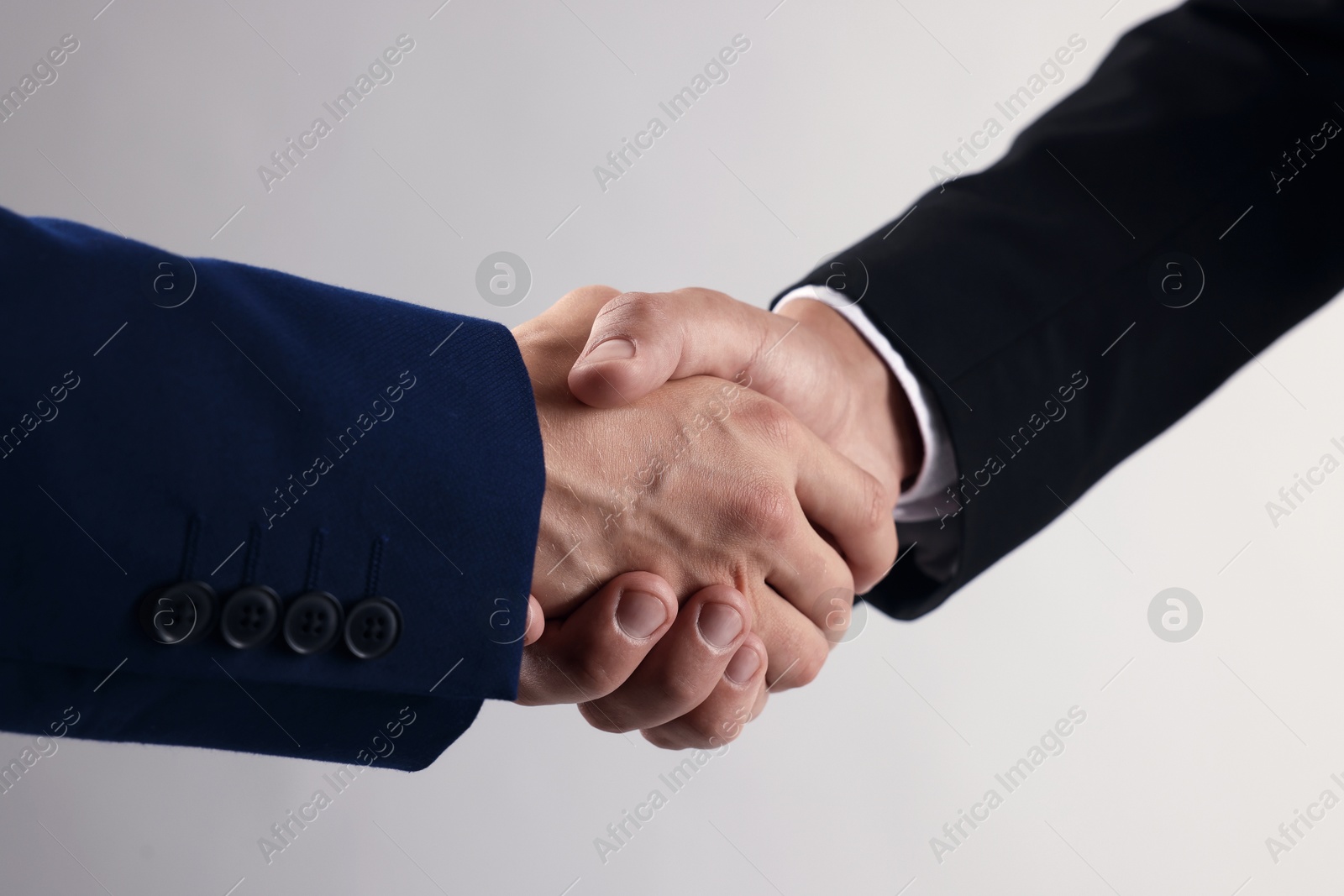 Photo of Business partners shaking hands on light grey background, closeup