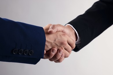 Photo of Business partners shaking hands on light grey background, closeup