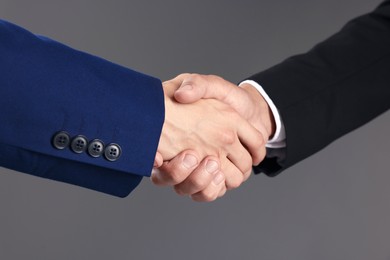 Photo of Business partners shaking hands on grey background, closeup
