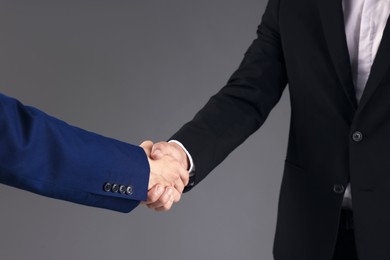 Photo of Business partners shaking hands on grey background, closeup