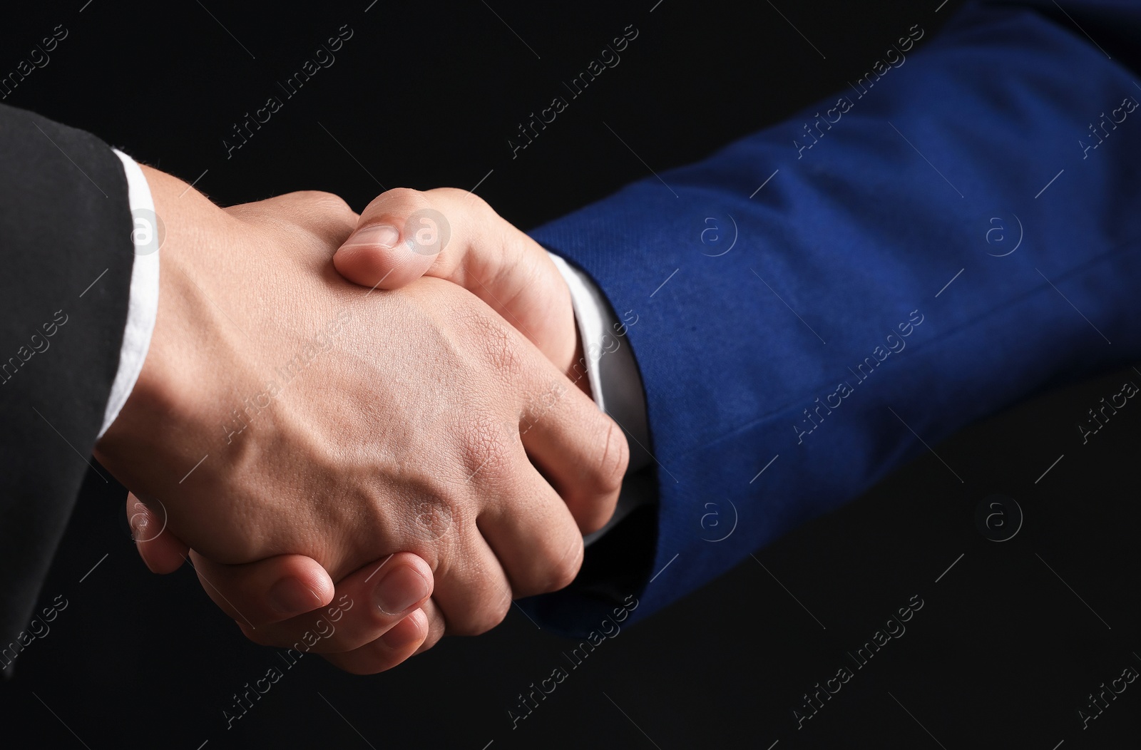 Business partners shaking hands on black background, closeup Photo of Business partners shaking hands on black background, closeup