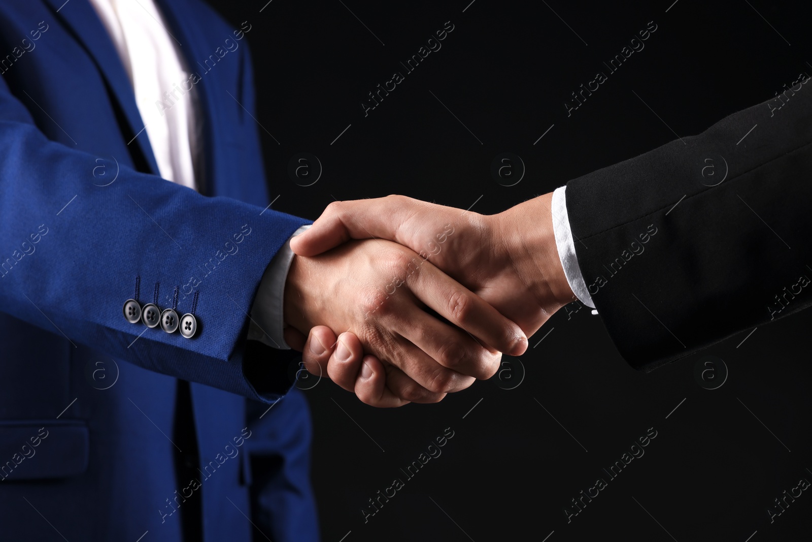 Business partners shaking hands on black background, closeup Photo of Business partners shaking hands on black background, closeup