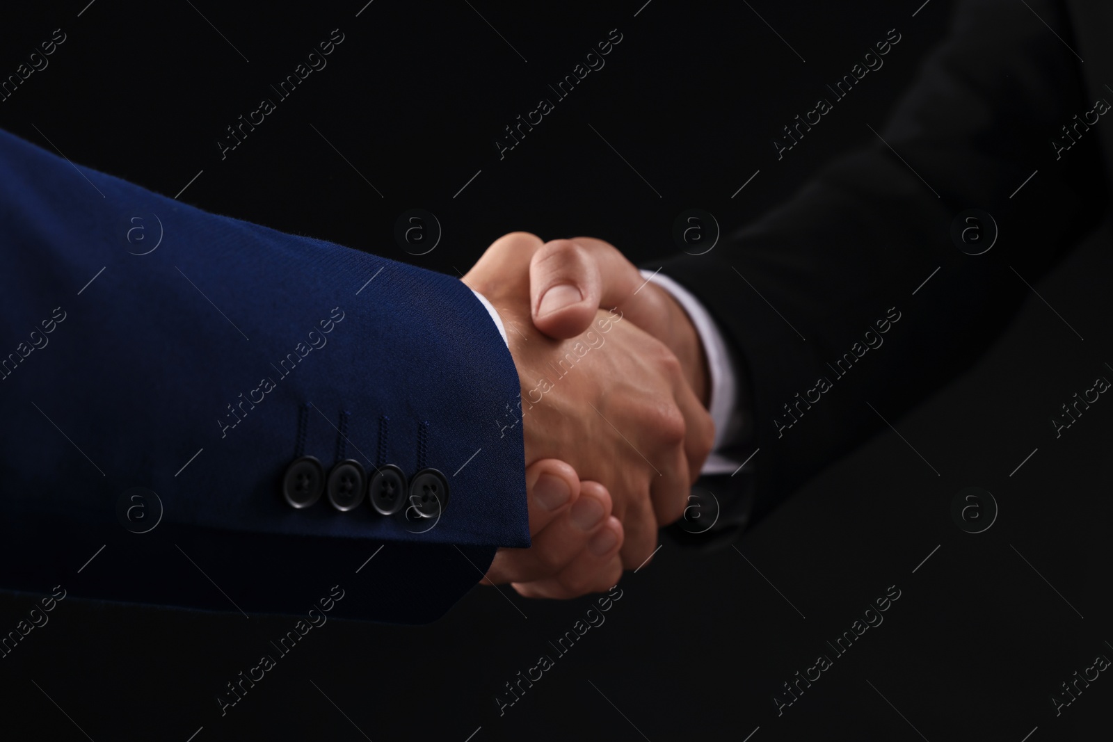 Business partners shaking hands on black background, closeup Photo of Business partners shaking hands on black background, closeup