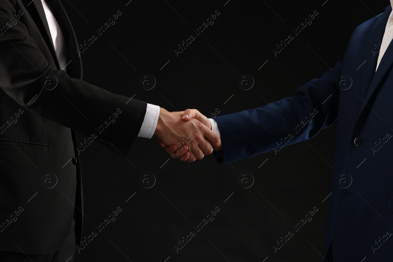 Business partners shaking hands on black background, closeup Photo of Business partners shaking hands on black background, closeup