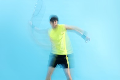 Photo of Man with racket playing tennis on light blue background, motion blur effect